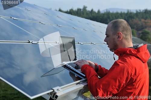 Image of engineer using laptop at solar panels plant field