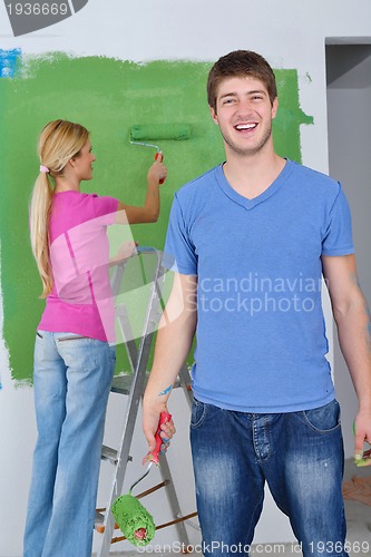 Image of happy couple paint wall at new home