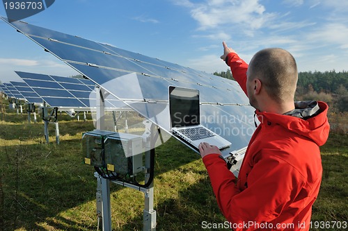 Image of engineer using laptop at solar panels plant field