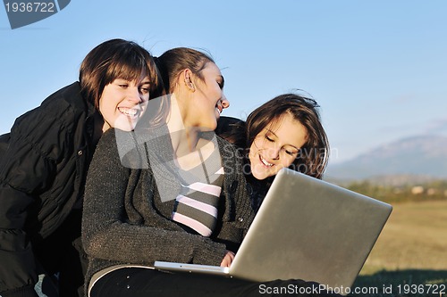 Image of group of teens working on laptop outdoor