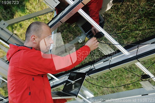 Image of engineer using laptop at solar panels plant field