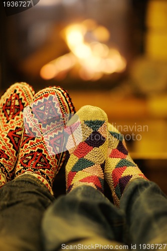 Image of Young romantic couple sitting and relaxing in front of fireplace