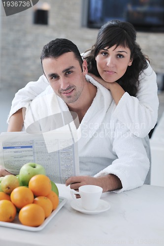 Image of Happy couple reading the newspaper in the kitchen at breakfast