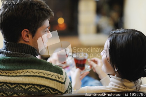 Image of Young romantic couple sitting and relaxing in front of fireplace