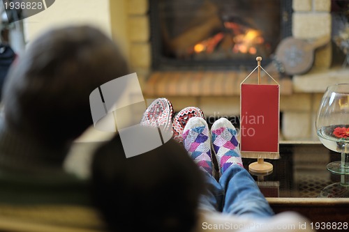 Image of Young romantic couple sitting and relaxing in front of fireplace