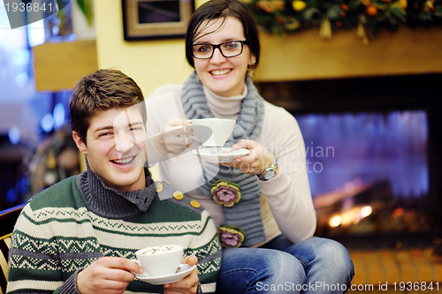 Image of Young romantic couple relax on sofa in front of fireplace at hom