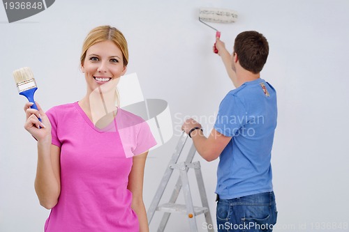 Image of happy couple paint wall at new home