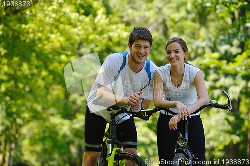 Image of Happy couple riding bicycle outdoors