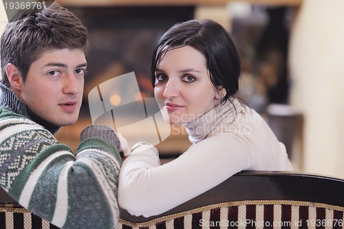 Image of Young romantic couple sitting and relaxing in front of fireplace