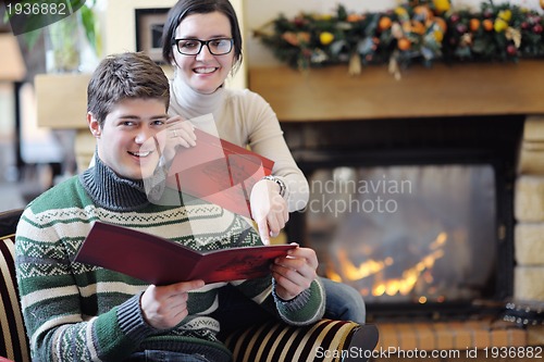 Image of Young romantic couple sitting and relaxing in front of fireplace