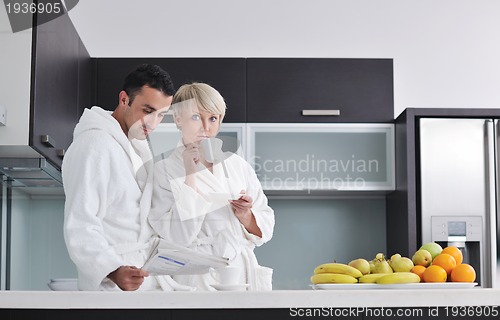 Image of Happy couple reading the newspaper in the kitchen at breakfast