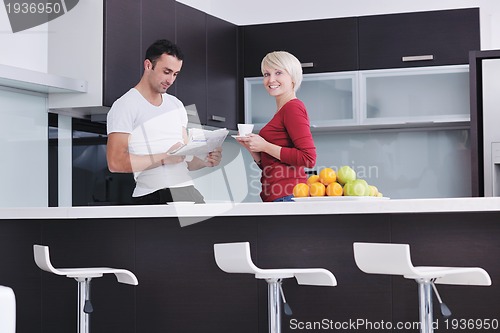 Image of Happy couple reading the newspaper in the kitchen at breakfast