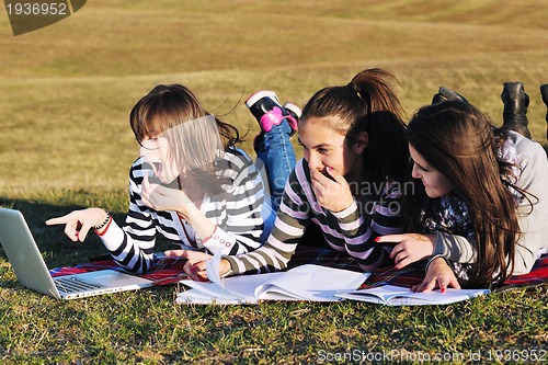 Image of group of teens working on laptop outdoor