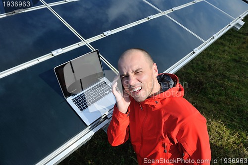 Image of engineer using laptop at solar panels plant field