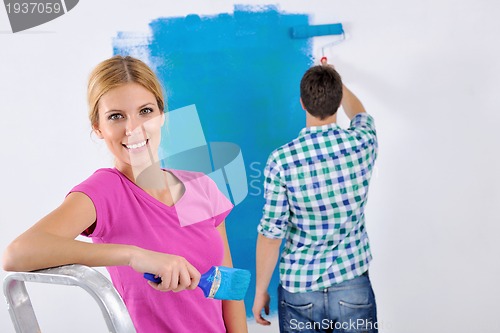 Image of happy couple paint wall at new home
