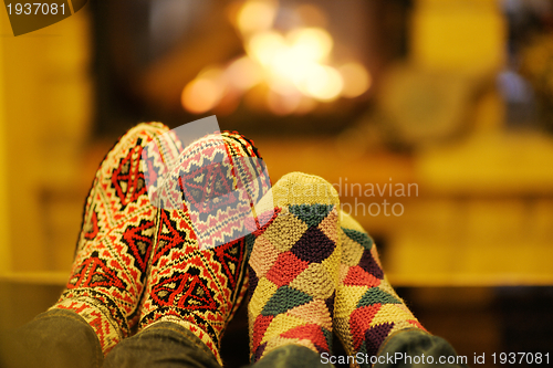 Image of Young romantic couple sitting on sofa in front of fireplace at h