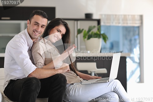 Image of joyful couple relax and work on laptop computer at modern home
