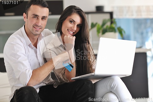 Image of joyful couple relax and work on laptop computer at modern home