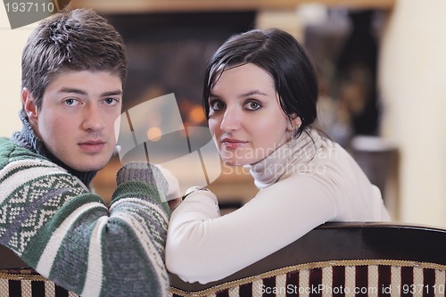 Image of Young romantic couple sitting and relaxing in front of fireplace