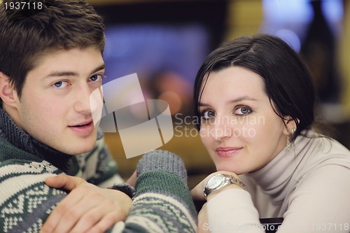 Image of Young romantic couple sitting and relaxing in front of fireplace