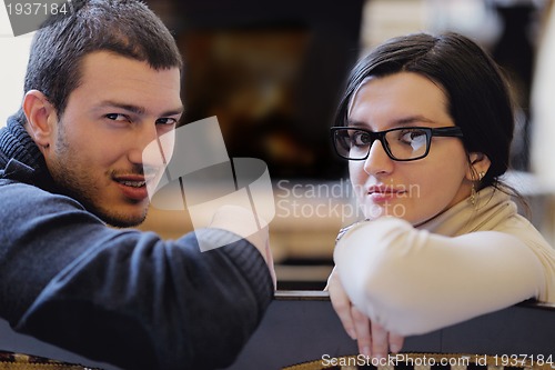 Image of Young romantic couple sitting and relaxing in front of fireplace