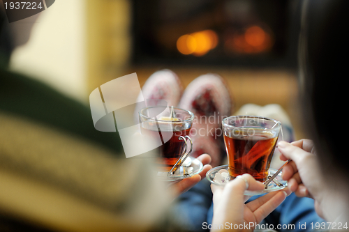 Image of Young romantic couple relax on sofa in front of fireplace at hom