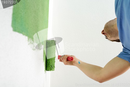 Image of handsome young man paint white wall in color