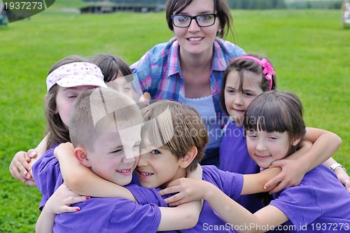 Image of happy kids group with teacher in nature