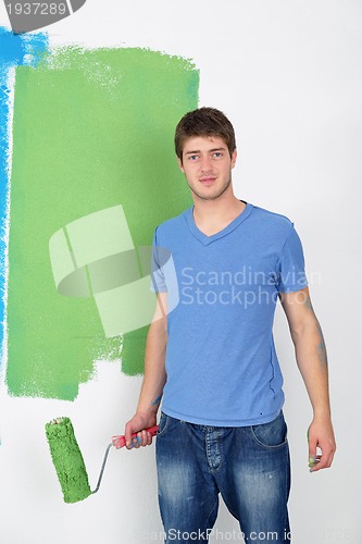 Image of handsome young man paint white wall in color