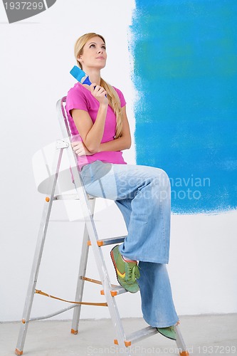 Image of happy smiling woman painting interior of house