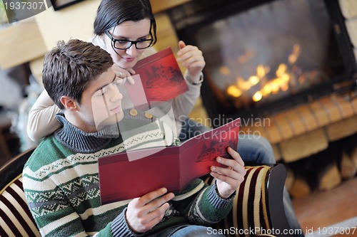 Image of Young romantic couple sitting and relaxing in front of fireplace