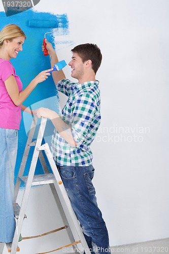 Image of happy couple paint wall at new home