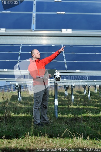 Image of engineer using laptop at solar panels plant field