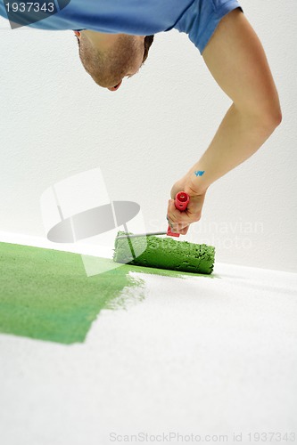 Image of handsome young man paint white wall in color