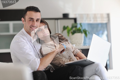 Image of joyful couple relax and work on laptop computer at modern home