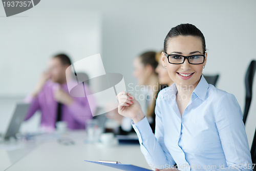 Image of business woman standing with her staff in background
