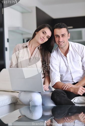 Image of joyful couple relax and work on laptop computer at modern home