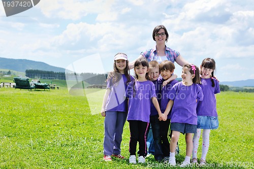 Image of happy kids group with teacher in nature