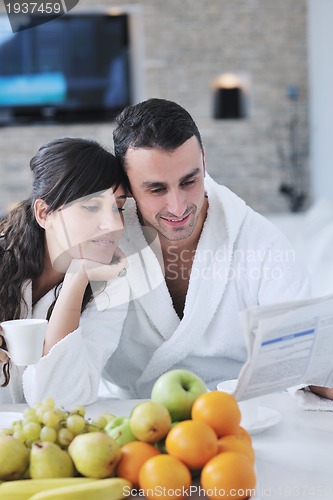 Image of Happy couple reading the newspaper in the kitchen at breakfast
