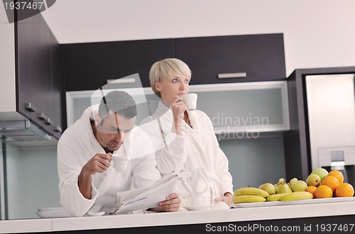 Image of Happy couple reading the newspaper in the kitchen at breakfast