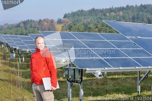 Image of engineer using laptop at solar panels plant field