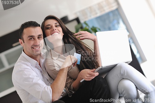 Image of joyful couple relax and work on laptop computer at modern home