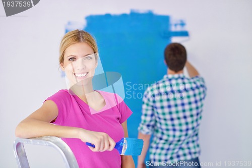 Image of happy couple paint wall at new home