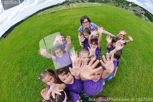 Image of happy kids group with teacher in nature