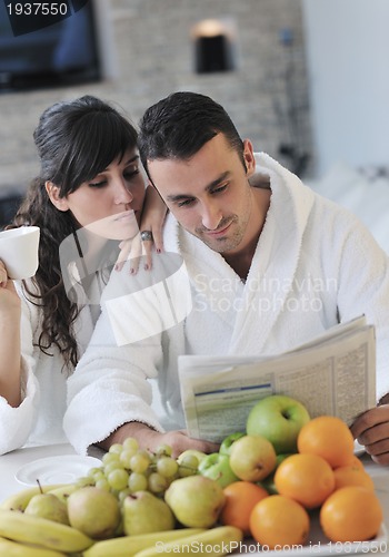 Image of Happy couple reading the newspaper in the kitchen at breakfast