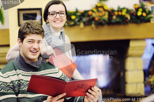 Image of Young romantic couple sitting and relaxing in front of fireplace