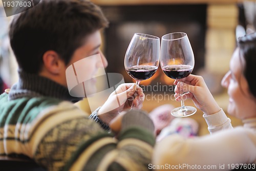 Image of Young romantic couple sitting and relaxing in front of fireplace