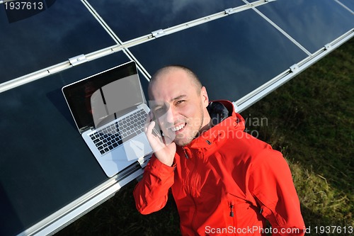 Image of engineer using laptop at solar panels plant field