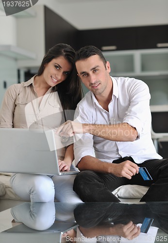 Image of joyful couple relax and work on laptop computer at modern home