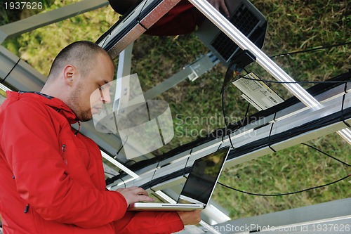 Image of engineer using laptop at solar panels plant field